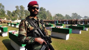 Un soldat pakistanais se tient près des cercueils de soldats tués.